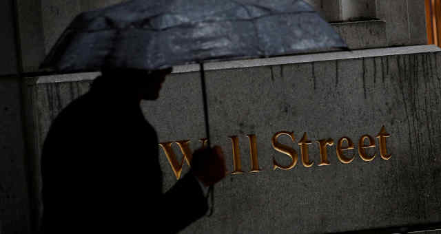 Homem caminha pela chuva em Wall Street do lado de fora da Bolsa de Nova York (NYSE), EUA. 09/10/2019. REUTERS/Brendan McDermid