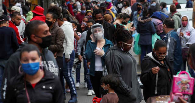 Mulher usando máscara protetora e protetor facial fala ao telefone enquanto pessoas caminham em uma popular rua comercial em meio ao surto de Covid-19 em São Paulo, Brasil, 15 de julho de 2020. REUTERS/Amanda Perobelli