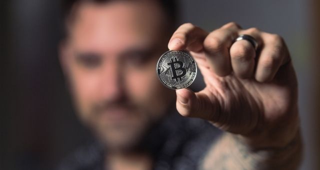 Homem segurando bitcoin na mão