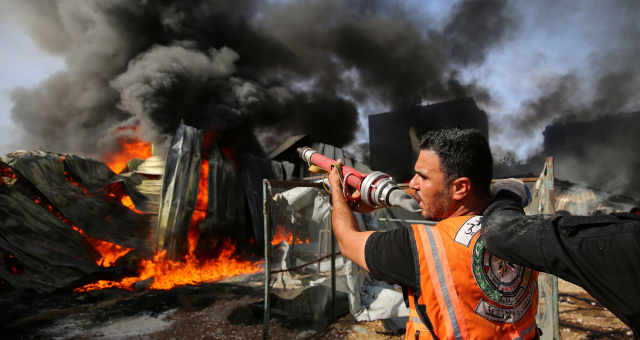 Bombeiros palestinos combatem chamas em fábrica atingida por ataque de Israel em Gaza 17/05/2021 REUTERS/Ashraf Abu Amrah