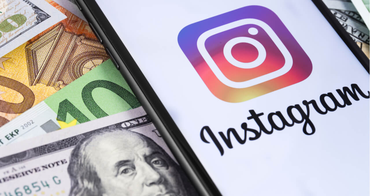 Um celular com o ícone do Instagram ao lado de cédulas de dinheiro, incluindo dólar