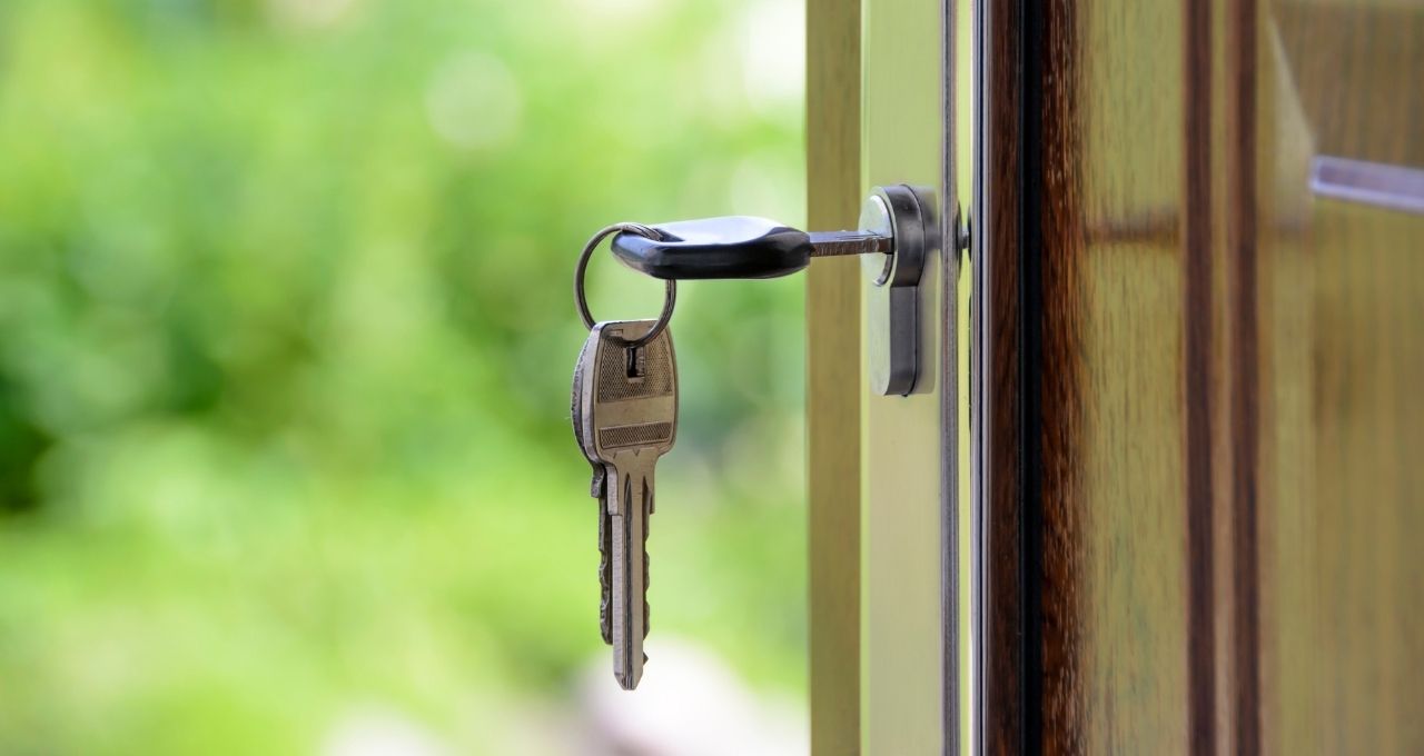 Foto mostra uma chave com chaveiro na porta