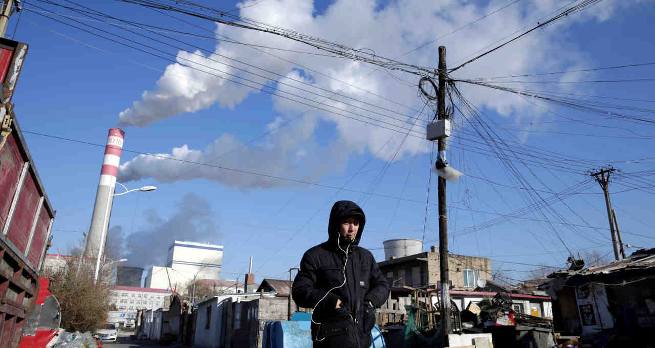 Homem caminha ao lado de usina de energia movida a carvão em Harbin, na China
