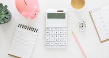 Mesa com calculadora, porquinho e blocos de anotações, representando gestão de dinheiro