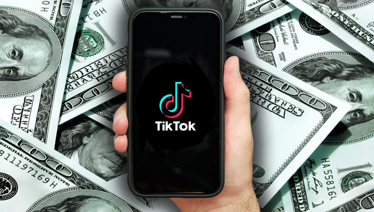 Celular com logo do TikTok aberto e notas de dólares ao fundo