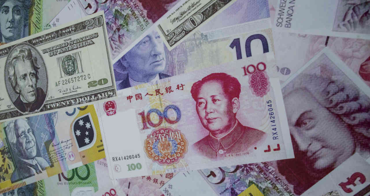 Notas de yuan são dispostas junto de notas de dólar e euro