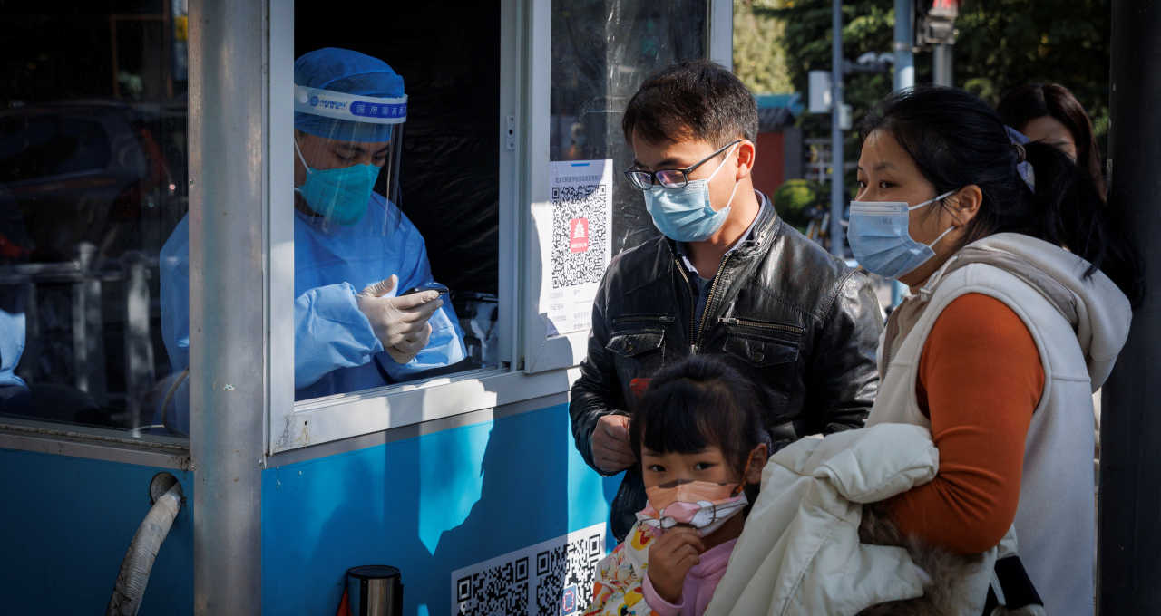 Funcionário colhe dados de pessoas em fila para teste de detecção de Covid-19 em Pequim