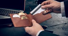 mão tirando cartão de carteira contendo criptomoedas e Bitcoin